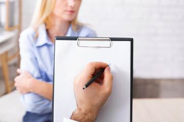 Psychotherapist clipboard. Doctor taking notes about health status of depressed millennial woman,...