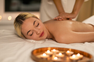 This photo shows a young woman at a spa, relaxing deeply while a therapist provides a soothing back massage, emphasizing relaxation and health.
