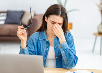 Stressed woman rubbing nose, showing sickness from overwork