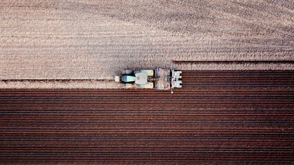 Tractor with seed drill stirs up dust in a field when sowing corn, agriculture, drill sowing, plant...