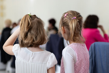Two little girls stand on their back and watch people into a restaurant