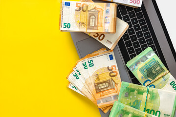 Sport betting app, online bets concept. Laptop with cash stacks on yellow background with copy...