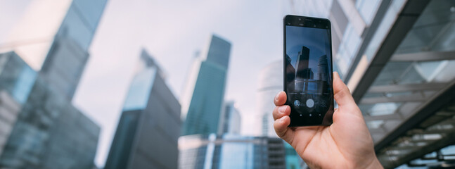 A male hand with a phone takes a picture against the backdrop of the city