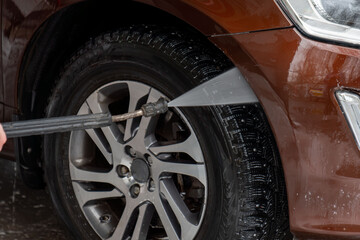 High pressured water. Modern brown automobile get cleaned inside of car wash station.