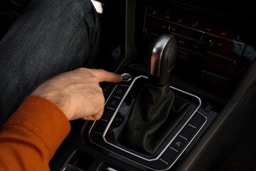 Closeup of male hand pushing on car start engine, touching button placed near gearbox