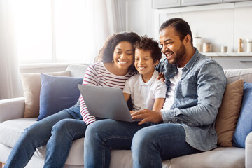 African American family consisting of a father, mother, and two children sitting comfortably on a...