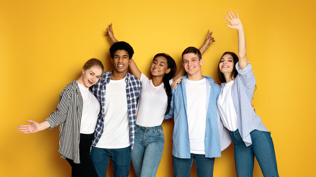 A diverse group of multiethnic teenagers standing close together in a social setting, engaging in conversation and interaction. Men and girls of different ages and ethnicities are seen together in the