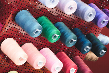 A rack of colorful spools of thread. The spools are of various colors and sizes. The spools are...