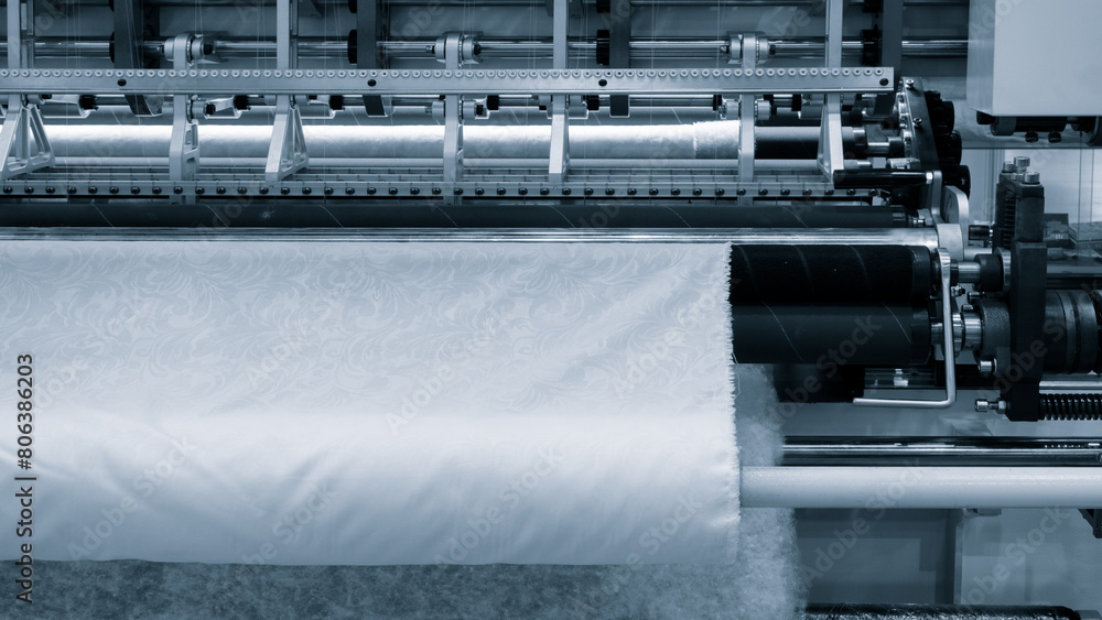 Poster A machine is weaving a fabric with many different colored threads. The machine is blue and white