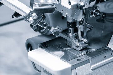 A sewing machine is in use, with a piece of fabric being sewn. The machine is black and silver, and...
