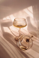 Two glasses with white wine placed on light beige background with shadows and fantastic highlights...