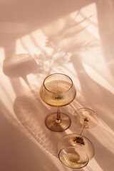 Two glasses with white wine placed on light beige background with shadows and fantastic highlights...