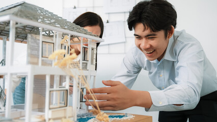 Closeup of young professional skilled architect engineer team focusing on checking the house model...