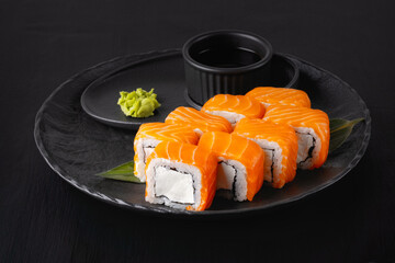 Philadelphia roll with salmon and cheese on plate on dark table