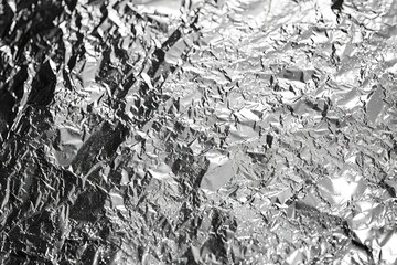 A piece of shiny silver foil with a lot of wrinkles and creases. The foil is crumpled and has a rough texture