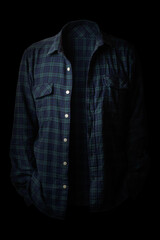 A person wearing a plaid shirt standing in the dark
