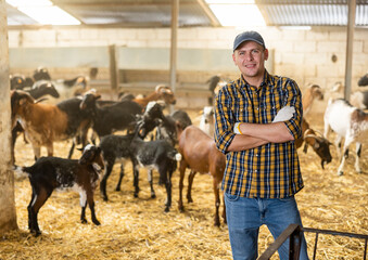 Portrait of positive male farmer standing with crossed hands on chest and smiling at camera on on...