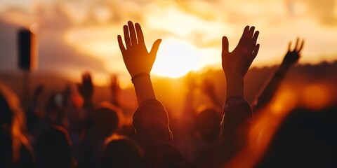 a crowd of people raising their hands up in the air with the sun setting