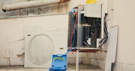 Handheld camera shot of damaged air cooling unit in need of fixing, with malfunctioning electric...