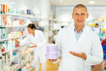 Male pharmacist offers medicine while standing in the trading floor of a pharmacy