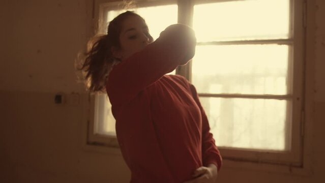 Woman in red does interpretive dance with window behind