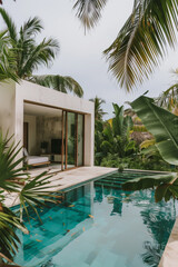 Obraz premium Outdoor pool area with modern furniture, surrounded by garden with tropical plants and trees