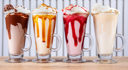 A row of colorful milk shakes in glass cups with handles