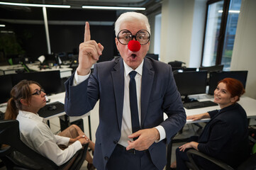 Fototapeta premium An elderly man in a clown costume fools around at work.