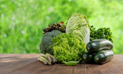 Harvest of fresh green vegetables lies on a wooden table, in summer.