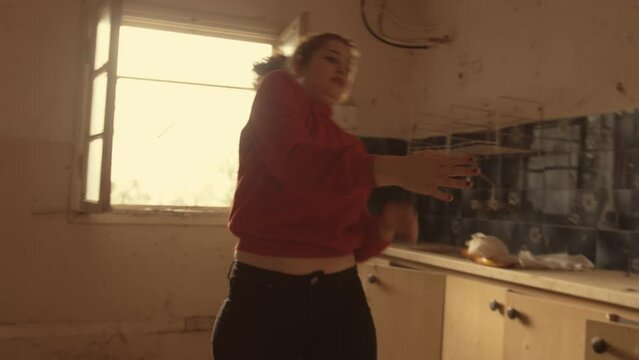 Woman does interpretive dance in a rundown house spinning