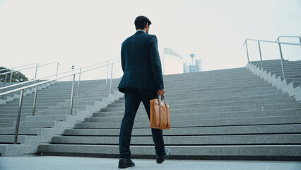 Top view of smart business man walking up stairs with bag in the hand. Professional project manager climb up the stair and going to workplace. Increasing skill, getting promotion, traveling. Exultant.