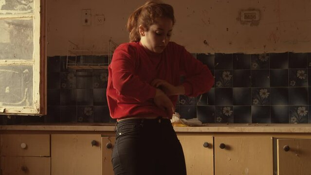 Woman in red does interpretive dance in a rundown kitchen