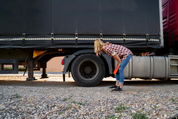 Female truck driver inspecting tires before the road 