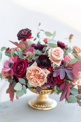 Floral arrangement of colorful roses, peonies, anemones, ranunculus and wildflowers in a vintage golden vase