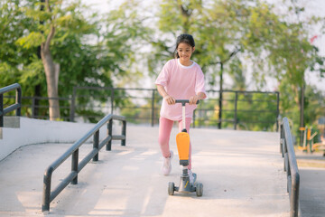 A young girl riding a scooter down a ramp