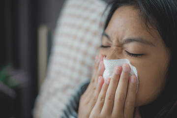 A woman is blowing her nose with a tissue