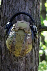 A tactical helmet and active tactical headphones hang on a tree branch. Defense of the military, military operations. War in Ukraine