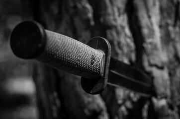 An army knife with a blade stuck in a tree.
A knife with a green rubberized handle and a black blade.
Black and white photo