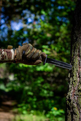 A military knife and a hand in tactical gloves holding it. Military affairs, tactical equipment.