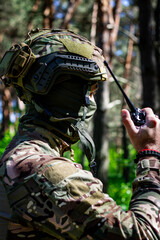 A military man in a tactical helmet and balaclava communicates on a walkie-talkie.
Military affairs, war in Ukraine. Combat actions, situational awareness