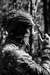 A military man in a tactical helmet and balaclava communicates on a walkie-talkie.
Military affairs, war in Ukraine. Combat actions, situational awareness
Black and white photo