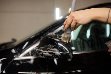 A person is cleaning a car windshield with a brush and water