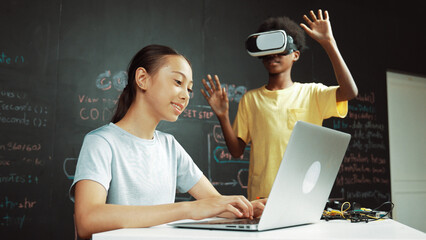 African boy wear headset to enter in metaverse while young beautiful academic student writing,...