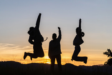 Three people jumping on mountain sunset sky background.