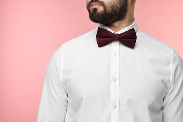 Man in shirt and bow tie on pink background, closeup
