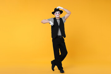 Funny mime artist in hat posing on orange background