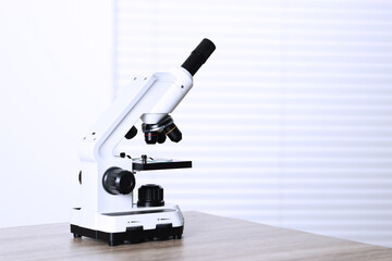 Modern microscope on wooden table. Space for text