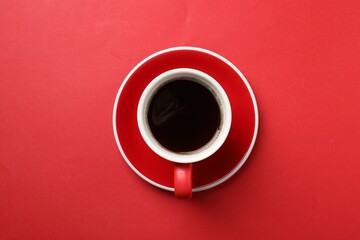 Aromatic coffee in cup on red background, top view