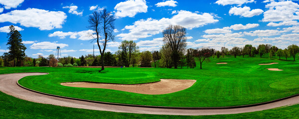 Spring landscape over the lush green fairway, sand bunkers, and swirling driveway at sunrise, a...