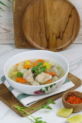 Chicken vegetables soup, Indonesian popular chicken soup, made from chicken meat, carrot, potato, and cabbage. served with sambal an lime slice. White marble background and copy space.